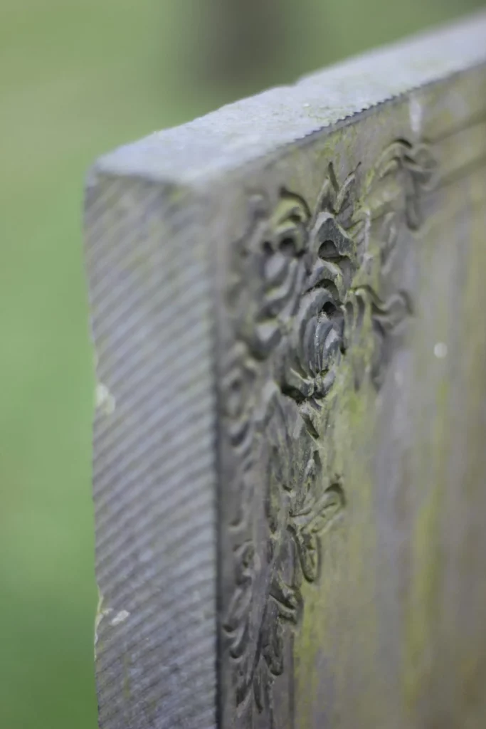 Ornement sculpté usé par le temps sur la tranche d’une stèle ancienne.