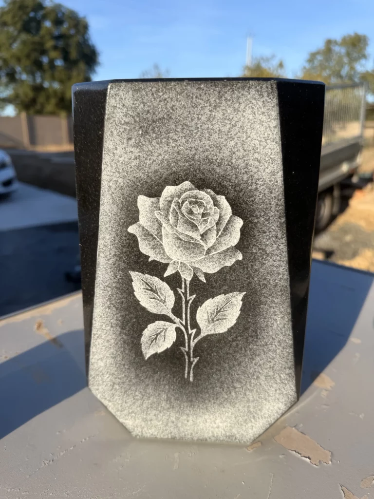 Rose gravée en grisé sur un vase en granit noir à pans coupés.